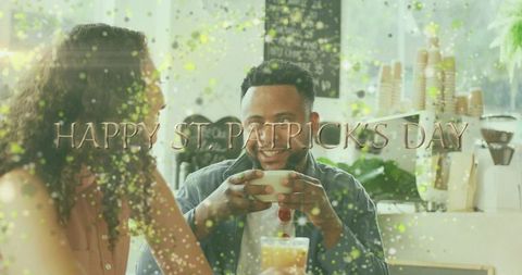 Couple enjoying coffee with st patrick's day confetti overlay in sunlit bright urban cafe