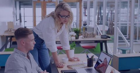 Creative team collaborating over laptop in modern open-plan office with natural light
