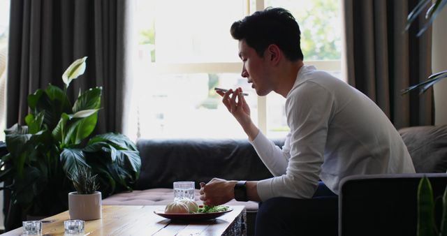 A young Asian man is enjoying a meal alone at a table, with copy space. His casual dining setting suggests a comfortable and relaxed atmosphere at home.