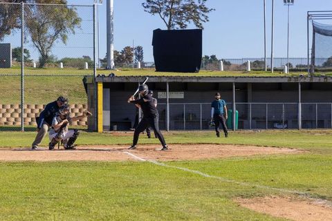 Batter swinging at incoming pitch with catcher blocking plate and umpire signaling strike