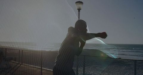 Athlete training boxing by ocean at sunset
