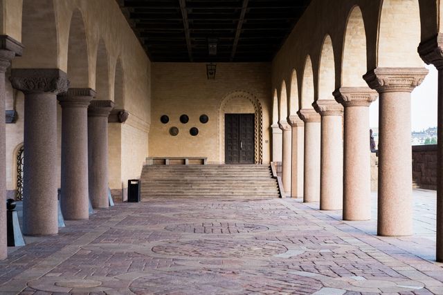 Historic stone building featuring rows of arches and columns in a spacious corridor. Ideal for themes around architecture, history, tourism, and cultural heritage. Perfect for educational content, travel guides, and historical presentations.