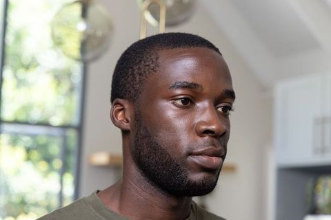 Thoughtful african american man looking out window in sunlit modern kitchen