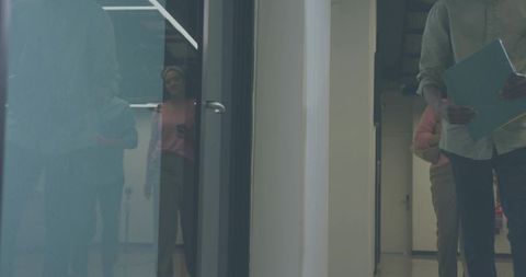 Holding blue folder in office corridor with glass reflection and walking colleagues