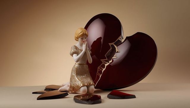 Artistic porcelain figurine kneeling by broken heart symbol