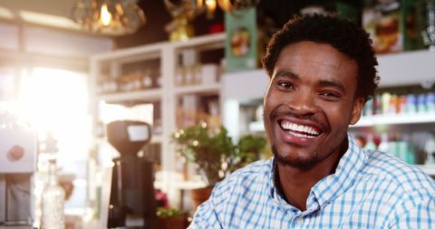 Smiling Man with Mobile Phone in Modern Café Atmosphere