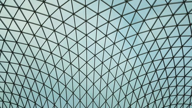 Geometric dome ceiling with a symmetrical grid pattern, made of glass panes with metal supports. Suitable for use in architectural design portfolios, modern art collections, abstract backgrounds, or as a design inspiration.