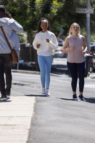 Diverse friends jogging on tree-lined street in athletic wear for urban fitness lifestyle