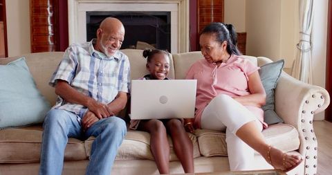Senior Grandparents and Young Girl Using Laptop at Home