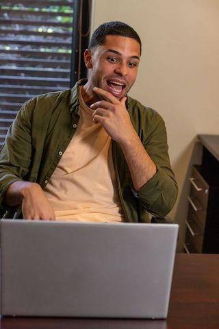 Focused African American Man Communicating at Home Office Desk with Laptop
