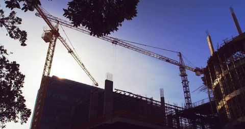 Tower Cranes Silhouetted Against Dusk Sky at Construction Site