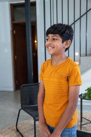 South asian boy standing indoors in casual mustard attire