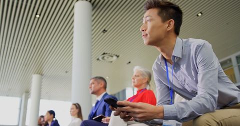Focused businessman using phone during seminar indoors