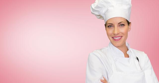 Portrait of female chef standing with arms crossed against pink background