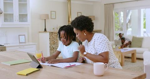 Mother and Son Learning Together at Home Using Tablet and Workbook