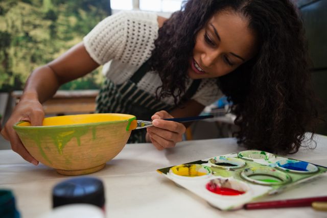 Beautiful woman painting bowl in drawing class