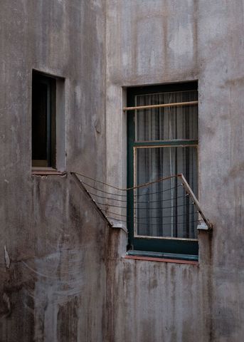 Weathered Window Displaying Rusted Clothesline on Textured Concrete Facade