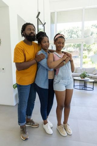 African american family embracing in modern bright living room wearing denim and sneakers