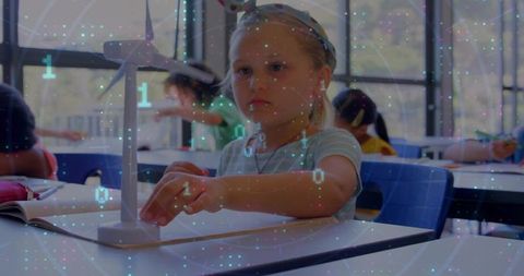 Blonde girl adjusting wind turbine model in classroom with digital data overlay for STEM