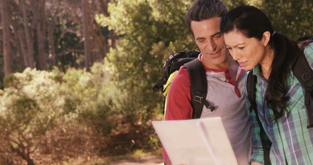 Couple hiking in wooded area studying map planning hiking route adventure in nature. This can be used for articles on travel, outdoor activities, and nature exploration.