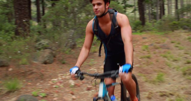 A young Caucasian man is actively mountain biking through a forested trail, with copy space - Download Free Stock Photos Pikwizard.com