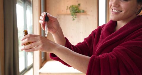 Woman applying serum with dropper near sunlit window