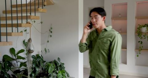 Asian man talking on smartphone in modern home interior