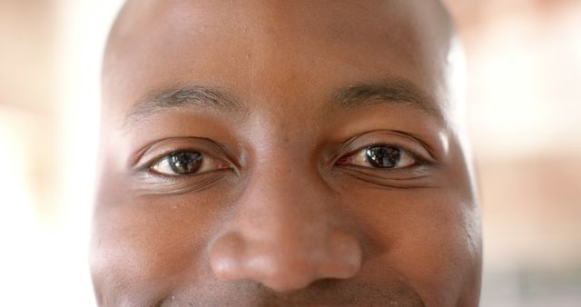This image captures a close-up of a man's face, focusing on his eyes and smile, radiating positivity and friendliness. It is ideal for use in websites, blogs, or marketing materials to convey concepts of happiness, friendliness, customer service, and human connection.