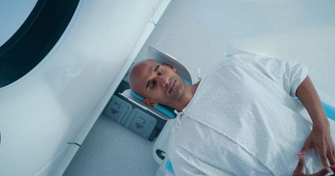African american man undergoing mri scan lying on motorized table with head support