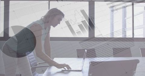 Businesswoman Analyzing Data on Laptop with Transparent Charts Overlay