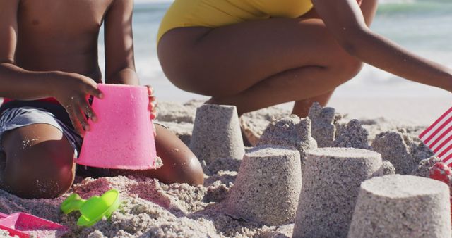 Children engaged in building sandcastles at beach, utilizing various sand toys. Creates feeling of summer fun, vacation, family time. Suitable for family vacation promotions, summer activities ads, travel blogs.