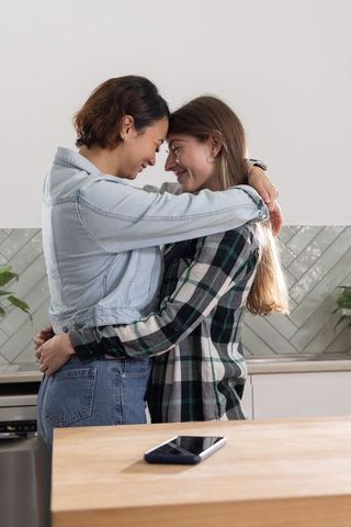 Intimate same-sex couple embracing foreheads at kitchen island warm domestic moment
