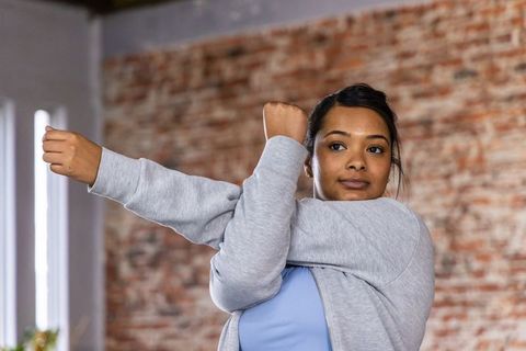 African american woman stretching in urban loft before workout