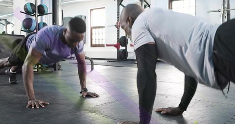 Duo doing push-ups and holding plank on gym mat with compression sleeve and wristwatch