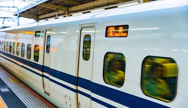 High-Speed Train Stopping at Platform with Digital Display and Blurred Passengers