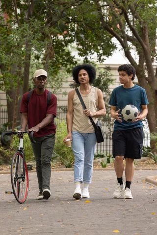 African american men walking in park pushing bicycle holding soccer ball casual urban