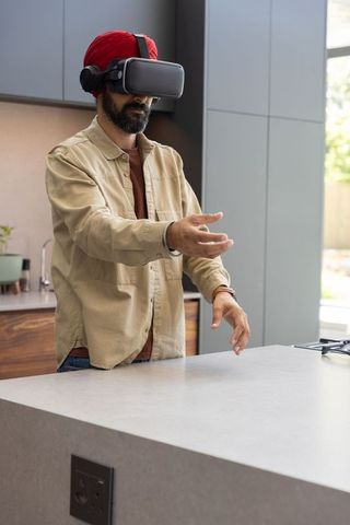 Man with vr headset manipulating virtual interface in modern kitchen