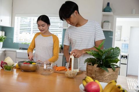 Asian couple preparing vegetables in modern kitchen interior