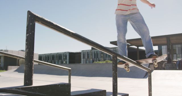 Teen boy skateboarding on rail in urban skate park. Captures dynamic action of skateboarding movement. Suitable for websites about sports, youth culture, and urban lifestyle. Ideal for articles or promotions on skateboarding events, tutorials, and athleticism in city environments.