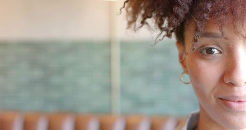 Closeup smiling african american woman facing camera in cafe with teal tile bokeh and copy space