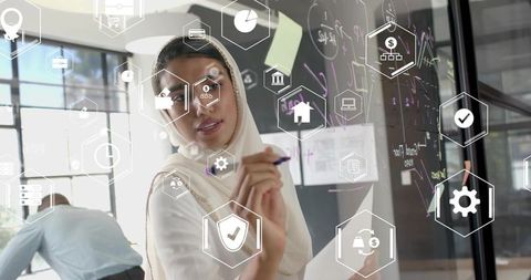 Businesswoman in Hijab Writing Formulas on Glass Board with Digital Icons