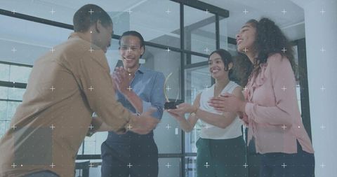 Team presenting award to colleague in modern office celebrating achievement