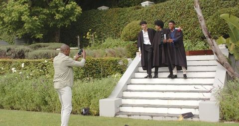 Proud Father Photographing Graduated Students on Garden Steps