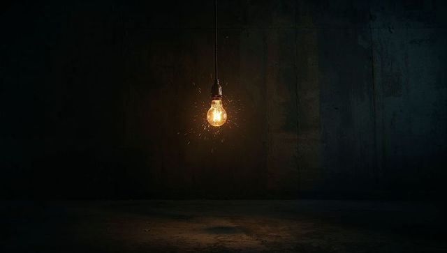 Hanging incandescent bulb in dark warehouse with sparks