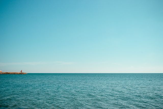 Tranquil ocean view extending to the horizon, underneath a clear blue sky. Ideal for backgrounds, relaxation visuals, travel promotions, and meditation content.