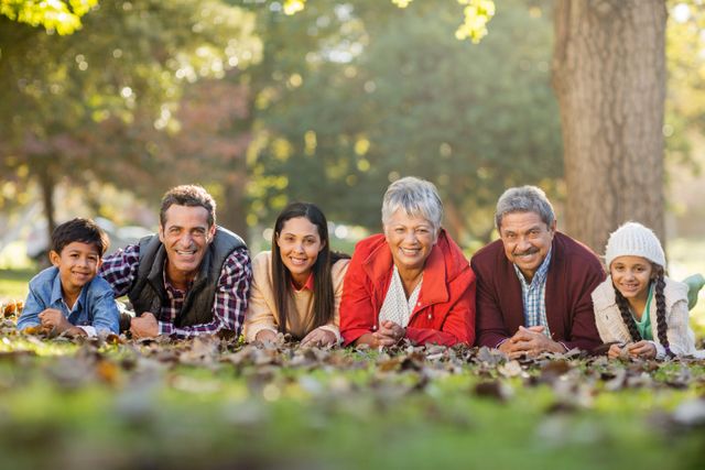 This image shows a happy multigenerational family lying on the grass in a park, enjoying a sunny autumn day. It is perfect for use in advertisements, family-oriented content, and promotional materials for parks or outdoor activities. It can also be used in articles or blogs about family bonding, outdoor leisure, and healthy lifestyles.