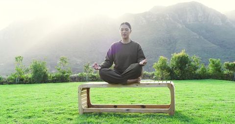 Woman Meditating on Bench with Mountain View in Tranquil Setting