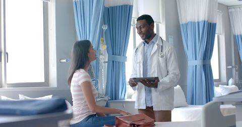 Doctor Consulting Patient with Tablet in Hospital Ward