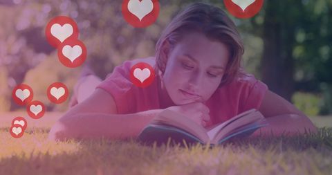 Woman relaxing on lawn reading book with heart icons