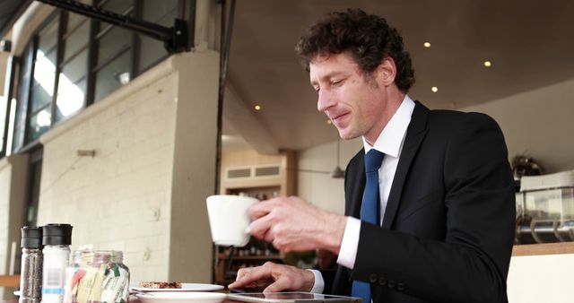 A Caucasian businessman in a suit is enjoying a cup of coffee at a cafe, with copy space. His focused expression suggests he might be contemplating work or taking a break from a busy day.